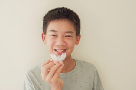 Asiatischer Junge mit weißem kieferorthopädischen Apparat